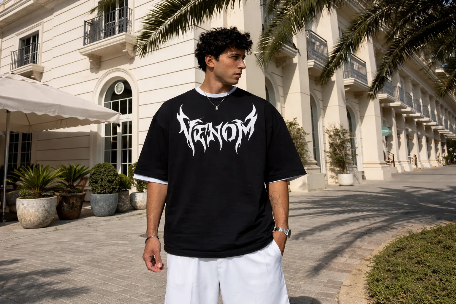 Man wearing a black t-shirt with 'Venom' logo outdoors.