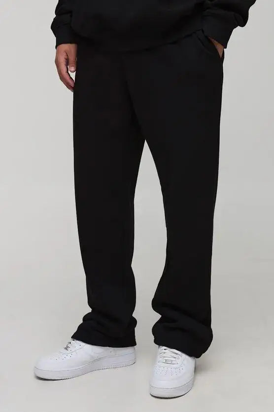 Person wearing black pants and white sneakers on a plain background